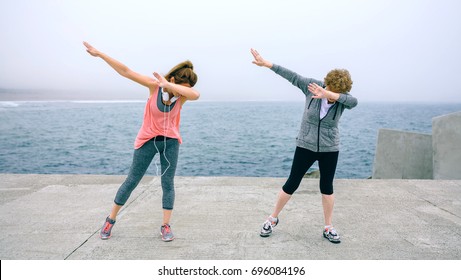 Senior And Young Woman Making Dab Dance Outdoors By Sea Pier