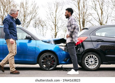 Senior and younger male drivers get out of cars and inspect damage after road traffic accident