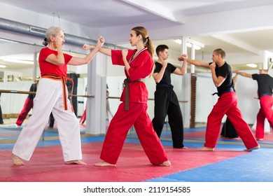 Senior and younger women sparring during group karate training. Adult man and teenage boy sparring in background. - Powered by Shutterstock