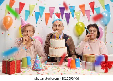 Seniors Celebrating A Birthday With A Cake And Party Horns