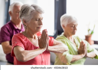 Seniors doing yoga with closed eyes in a retirement home