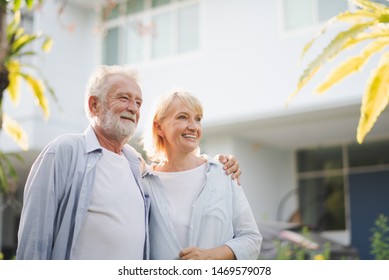 Seniors European couple man and woman are standing at outdoor green garden in retirement home. Retired couple are smiling felling happy and looking out of camera.