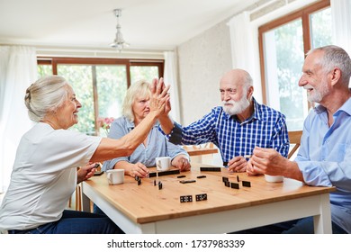 Seniors give themselves a high five when playing dominoes in a competition - Powered by Shutterstock