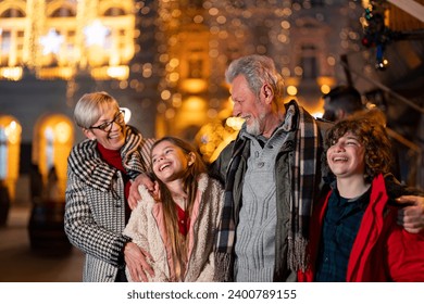 Seniors having a walk with grandkids at Christmas market, cheerfully smiling while exploring around. - Powered by Shutterstock