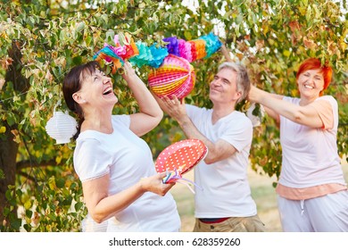 Seniors Laughing And Having Fun While Decorating For A Birthday Party In The Park