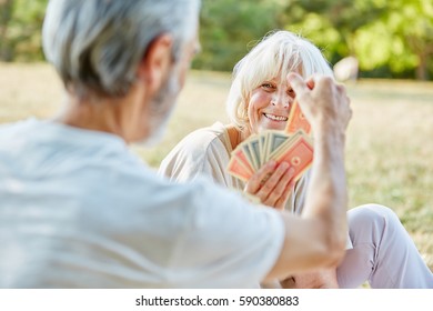 Seniors Playing Cards Together In The Garden In Summer