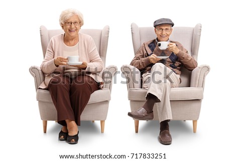 Seniors seated in armchairs drinking tea and looking at the camera isolated on white background