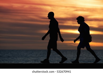 Seniors walking brisk walk along the shore at sunset - Shutterstock ID 532670941