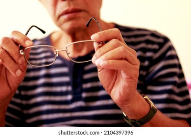 sennior man picks up eyeglasses to wear before reading in the room of the house