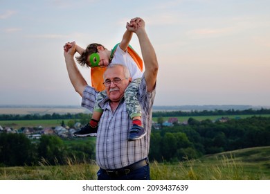 Senor man rolls on the shoulders of his little grandson. a little boy imagines that he is flying like a hero. fun family trips. - Powered by Shutterstock