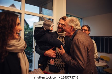 Senor man welcoming smiling awaited guests at the doorway during Christmas. Family coming over for Christmas dinner at the grandparents. - Powered by Shutterstock