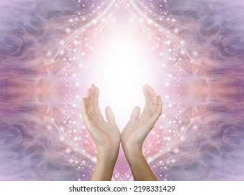 Sensing High Frequency Love And Light Healing Energy - Open Female Hands With White Light Between Against Beautiful Purple Pink Peach Sparkling Energy Field Background And Copy Space 
