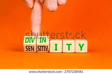 Sensitivity or divinity symbol. Concept words Sensitivity or Divinity on wooden cubes. Beautiful orange background. Psychologist hand. Psychology sensitivity or divinity concept. Copy space.