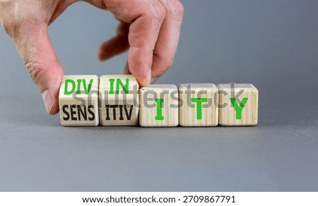 Sensitivity or divinity symbol. Concept words Sensitivity or Divinity on wooden cubes. Beautiful grey background. Psychologist hand. Psychology sensitivity or divinity concept. Copy space.