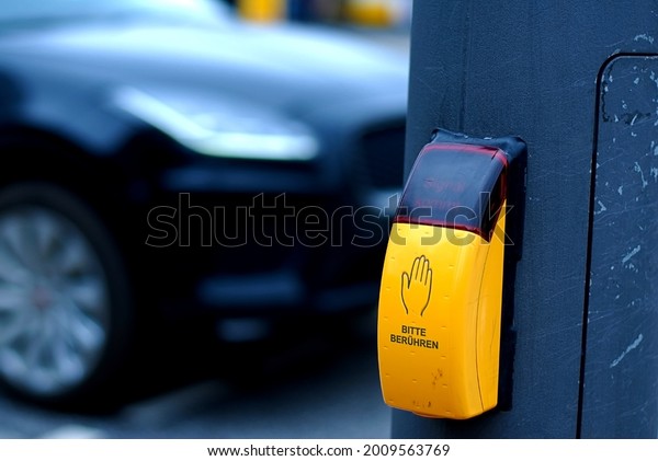 \
Sensor for manual activation of a traffic\
light in Germany. Touch switch for traffic lights on the background\
of the road. Roads in\
Germany.