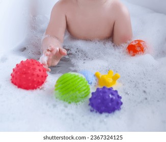 Sensory Balls for Children's Cognitive and Physical Development, Including Bathroom. the child's hand holds the ball. games in the bathroom - Powered by Shutterstock