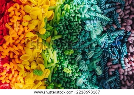 Sensory bin with dried pasta in rainbow colors. Dyed pasta for play and craft activities. Montessori material. Sensory play and learning colors activity for kids. 