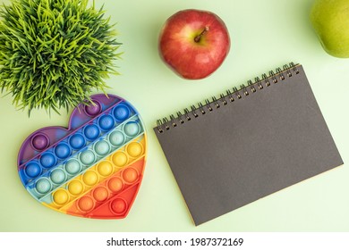 Sensory Fidget Toy, Notebook, Apple Over Green Background. Antistress Concept.