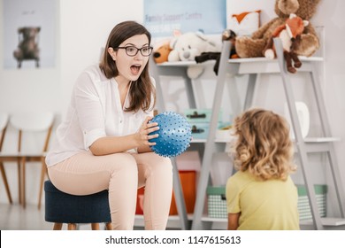 A Sensory Game With A Blue Ball Played By A Professional Child Therapist With A Kid In A Family Support Center.