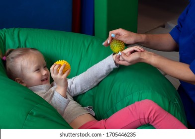 sensory therapist massaging little girl patient with a little ribbed ball