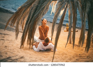 Sensual. Attractive couple having sex on the beach. Sex on beach concept. Couple full of desire have sex on sand of seashore. Sensual lovers making love at seashore, sea on background. Vacation. 