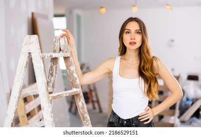 Sensual Attractive Young Woman With Long Wavy Brown Hair Wearing Tight Black Denim Shorts And White Tank Top Standing Leaning 