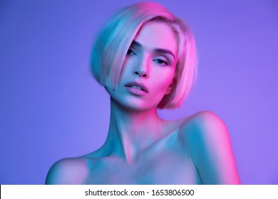 Sensual  blond young woman with  perfect skin in trendy glowing neon pink purple light. High fashion beauty luxurious mystical portrait in studio