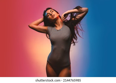 Sensual Brunette Woman Studio Portrait Wearing Black And White Stripes Body. Colored Gel Photography.