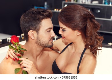 Sensual couple with rose in jacuzzi, looking each other, honeymoon