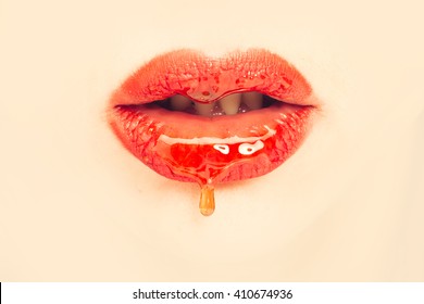 Sensual female red lips with honey closeup on beige background
