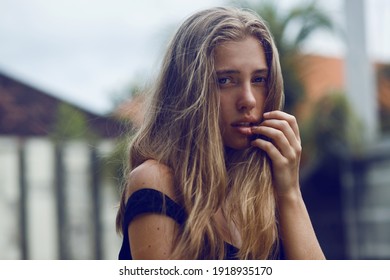 sensual portrait in dark colors of sad young woman with long hair outdoor