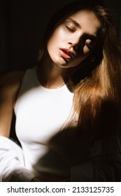 A Sensual Portrait Of A Young Attractive Woman With Perfect Skin In A Beam Of Light And A Dark Background.