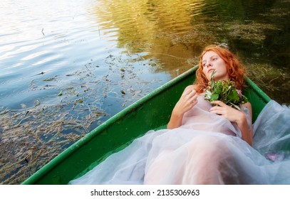 Sensual, Seductive, Young Sexy Red-haired Woman, With Longing Dreamy Look, With White Dress, Lying In A Boat Like A Redhead Siren In An Old Symbolist Painting, Copy Space