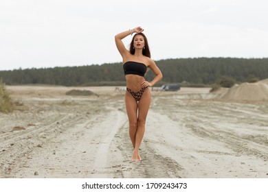 Sensual slim female in black swimsuit on beach