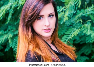 Sensual Smiling Young Woman With Gray Eyes And An Ombre Hairstyle Mix Of Dazzling Color Tones, Wearing A Silver Nose Ring And Glancing Sensually Into Camera At A Green Park.