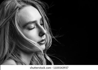 sensual woman with closed eyes and bare shoulders on black background with copy space, monochrome