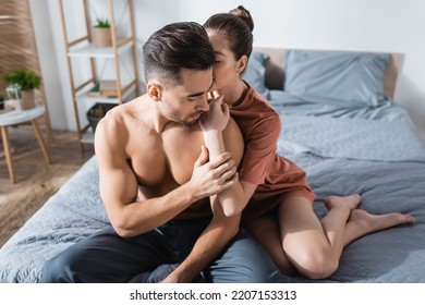 Sensual Woman Hugging And Kissing Sexy Shirtless Man Sitting On Bed In Pajama Pants