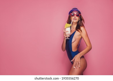 Sensual woman in swimwear with drink on pink