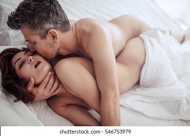 Sensual young couple making love in bedroom. Romantic man and woman having intimate sex in bed