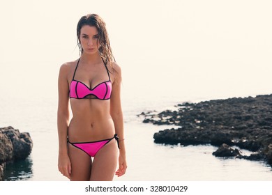 Sensual young woman portrait wearing pink bikini on the beach. Filtered image instagram style.