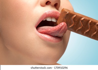 A Sensual Young Woman With Tasty Lips Licking A Chocolate Bar.