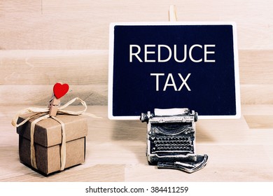 Sentence Reduce Tax Written With Chalk On A Blackboard, On A Table With Typewriter