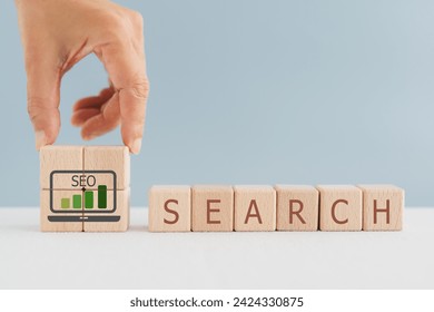 For SEO abbreviation for Search Engine Optimization, hand arranged graph and SEO text inside notebook icon on wooden cube block including copy space