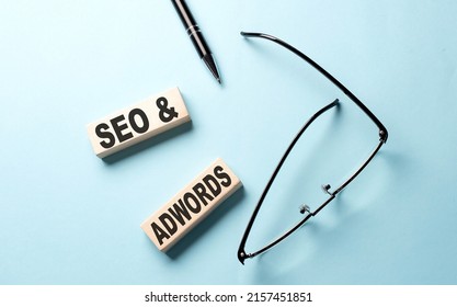 SEO AND ADWORDS text on wooden block ,blue background