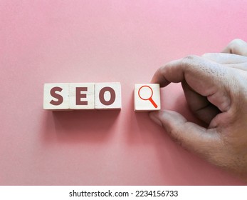 SEO concept on wooden cubes with magnifying glass against pink background. - Shutterstock ID 2234156733