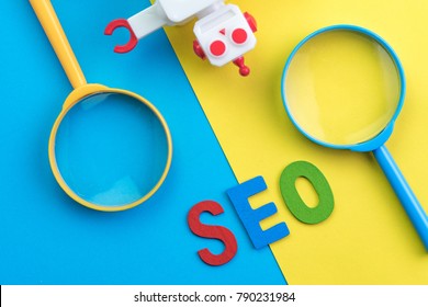 SEO Search engine optimization concept with blue and yellow magnifying glass, alphabet abbreviation SEO and robot on colorful background.