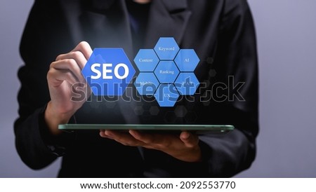SEO Search Engine Optimization concept, Human hand pointing promoting ranking traffic on website, optimizing your website to rank in search engines or SEO on virtual screen over tablet.