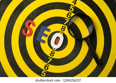SEO Search Engine Optimization multi color logo alphabets ranking concept on dartsboard background with magnifying glass, SEO is one of online marketing business strategy to promote website.