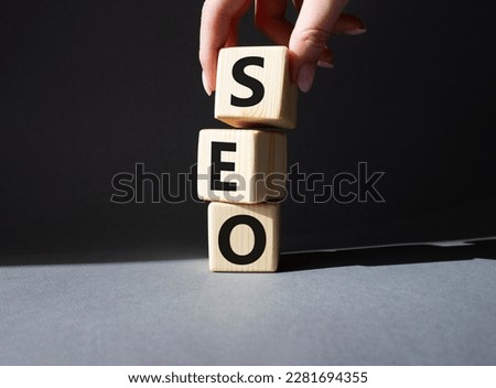 SEO - Search Engine Optimization symbol. Wooden blocks with words SEO. Businessman hand. Beautiful grey background. Business and SEO concept. Copy space.