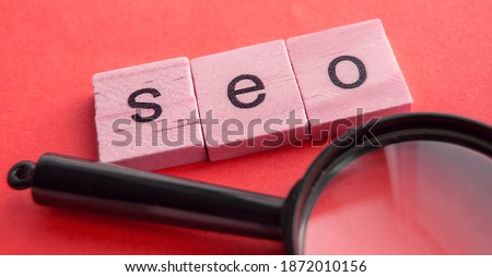 SEO search engine optimization text wooden cubes and magnifying glass on a red background. Idea, vision, strategy, analysis, Keyword and content concept.